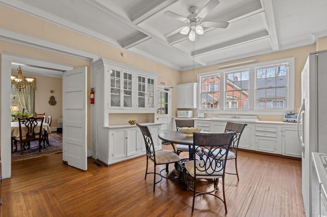Dining area featuring coffered ceiling, a chandelier, a ceiling fan, crown molding, and light wood-style flooring | Image 8