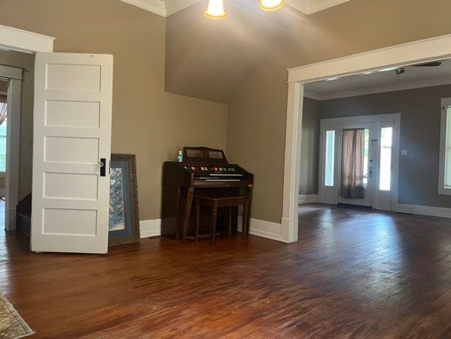 Unfurnished living room featuring crown molding and dark wood-style flooring | Image 7