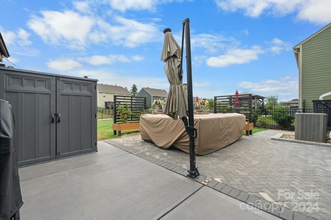 Patio was expanded and features herringbone pavers, embedded lighting, large umbrella, gazebo, stone fireplace, custom planters. Gray storage unit to left does not convey. | Image 34