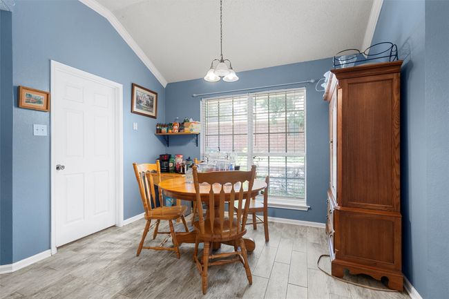 Dining space with lofted ceiling, ornamental molding, light wood-type flooring, a chandelier, and baseboards | Image 4