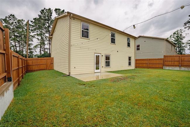 Fully privacy fenced backyard with stained and maintained fencing. Nicely sized concrete pad was an upgrade along with the fencing! Notice that the home has seamless upgraded gutters on front and back. The party lights convey with the home! | Image 27