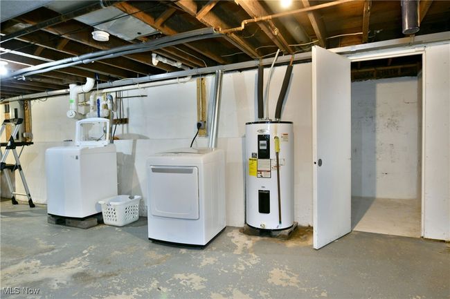 Unfinished basement with electric water heater and washer and clothes dryer | Image 38