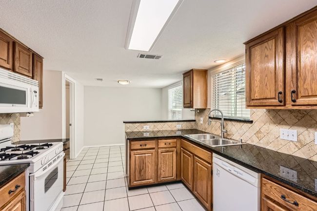 Kitchen featuring a sink, brown cabinetry, and white appliances | Image 9
