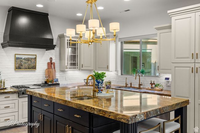Kitchen with wall chimney exhaust hood, a sink, a kitchen island with sink, stainless steel gas cooktop, and recessed lighting | Image 16