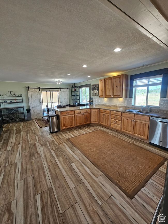 Kitchen featuring stainless steel appliances, granite countertops, a bar, decorative backsplash, knotty alder cabinets and beautiful flooring | Image 34
