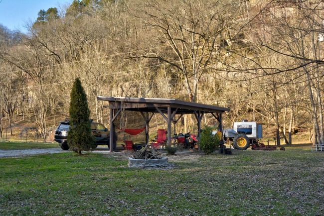 A concrete pad with a roof covering over it has electric and is wired for fans. A fire pit is in the foreground. | Image 12