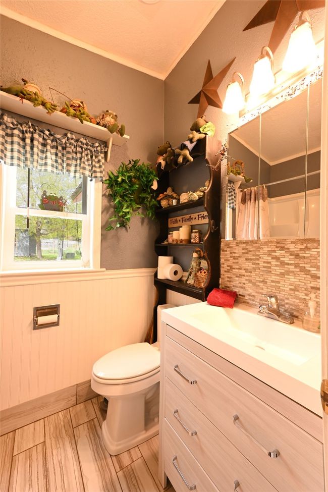 Bathroom featuring toilet, a wainscoted wall, vanity, decorative backsplash, and a shower with curtain | Image 24
