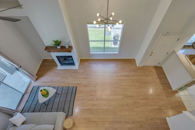 Living room featuring wood finished floors, a chandelier, and a tile fireplace | Image 32