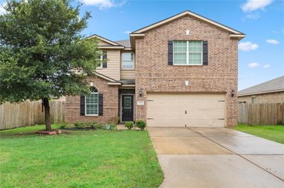 This is a two-story brick home with contrasting trim, featuring a prominent front window with shutters and a welcoming front door. | Image 2