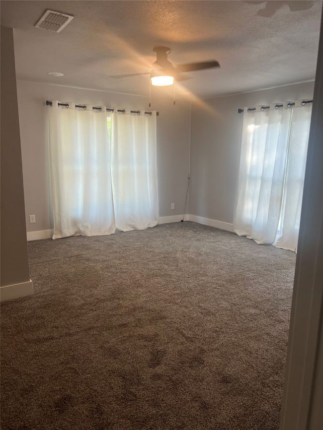 Carpeted spare room featuring ceiling fan, plenty of natural light, and a textured ceiling | Image 8