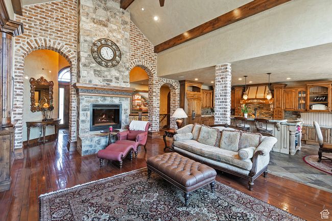 Living area featuring arched walkways, dark wood-style flooring, decorative columns, beamed ceiling, and high vaulted ceiling | Image 17