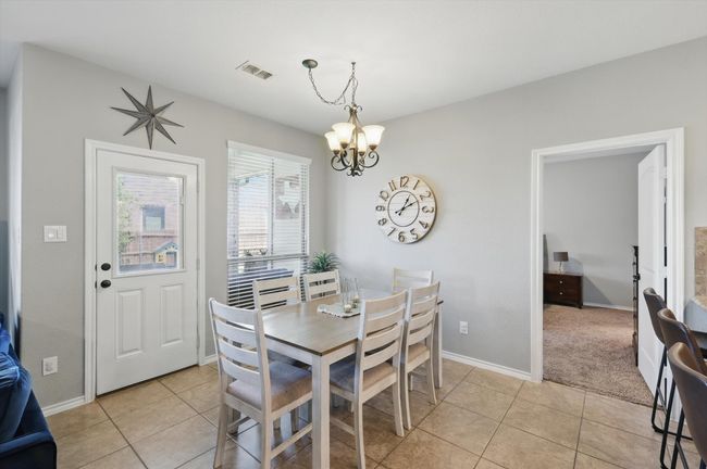 Dining space with a chandelier, light tile patterned floors, visible vents, and baseboards | Image 12