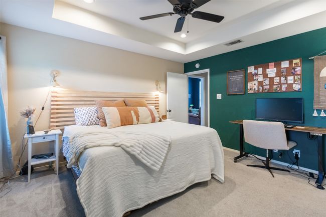 Carpeted bedroom featuring a raised ceiling, a desk, recessed lighting, and ceiling fan | Image 15