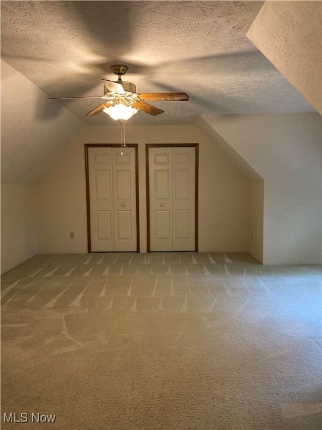 Additional living space with light carpet, a ceiling fan, a textured ceiling, and lofted ceiling | Image 17