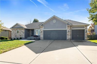 Ranch-style house with a front lawn and a garage | Image 1