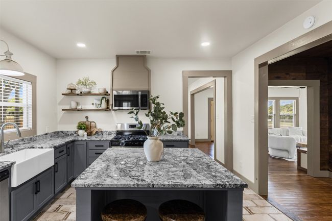 Kitchen featuring stainless steel appliances, open shelves, a sink, gray cabinetry, and light stone countertops | Image 17