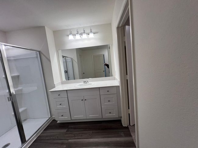 Full bath featuring a shower stall, wood finished floors, vanity, and a textured wall | Image 16