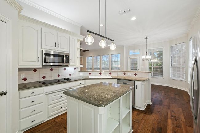 Kitchen featuring appliances with stainless steel finishes, open shelves, a peninsula, backsplash, and a kitchen island | Image 6