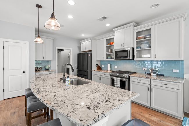 Kitchen with appliances with stainless steel finishes, a kitchen bar, backsplash, recessed lighting, and glass insert cabinets | Image 9