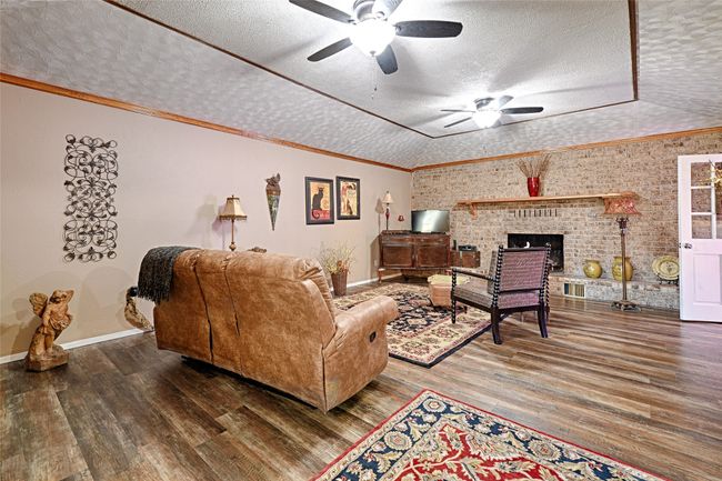 Living room featuring a textured ceiling, hardwood / wood-style flooring, ceiling fan, and ornamental molding | Image 22