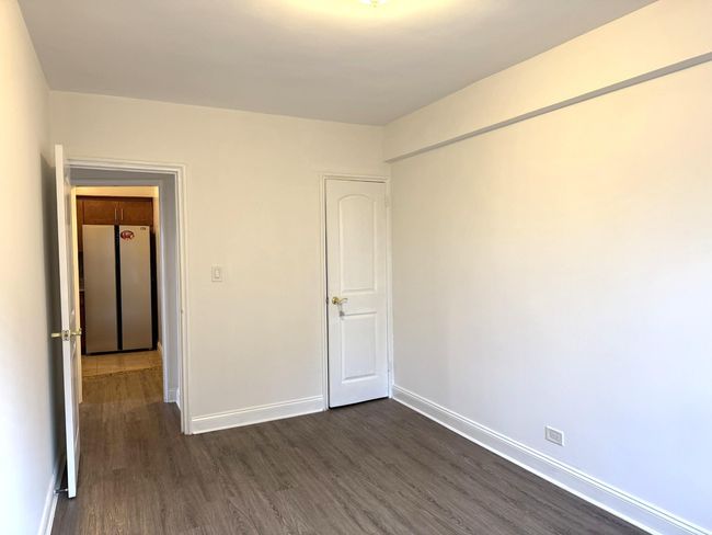 Unfurnished bedroom with freestanding refrigerator and dark wood-style floors | Image 17