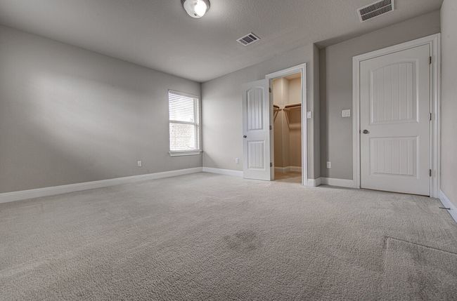Unfurnished bedroom with carpet, a walk in closet, and a closet | Image 23