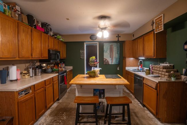 Kitchen featuring stainless steel appliances, light countertops, a ceiling fan, a sink, and brown cabinets | Image 8