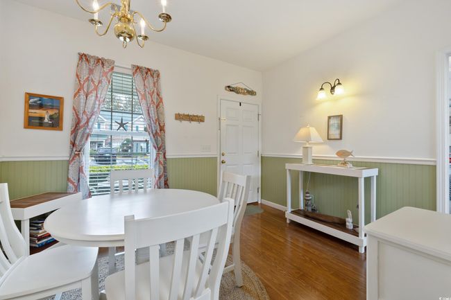 Dining area with a wainscoted wall, a chandelier, and wood finished floors | Image 11
