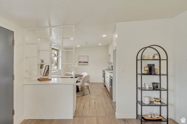 Kitchen with white cabinets, light wood-type flooring, stainless steel electric range, baseboards, and light countertops | Image 7