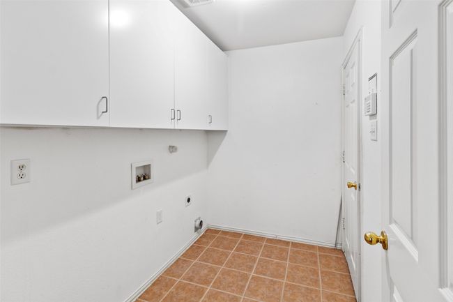 Clothes washing area featuring electric dryer hookup, cabinet space, hookup for a washing machine, light tile patterned floors, and baseboards | Image 36