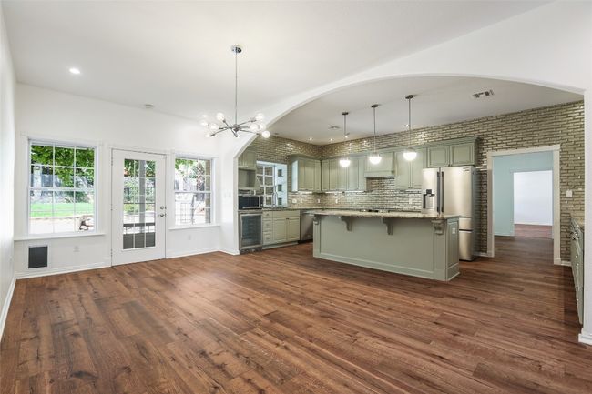 Kitchen with wine cooler, appliances with stainless steel finishes, arched walkways, dark wood-style floors, and recessed lighting | Image 4