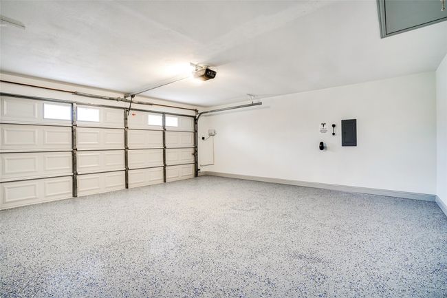 Garage featuring electric panel, a garage door opener, and baseboards | Image 28