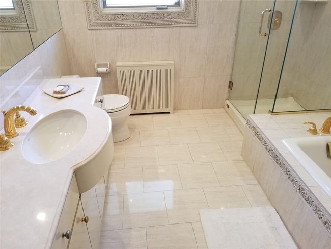 Bathroom with tile patterned floors, toilet, radiator, a shower stall, and vanity | Image 11