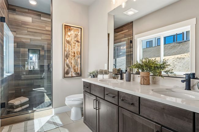 Bathroom featuring toilet, double vanity, a stall shower, tile patterned flooring, and baseboards | Image 50