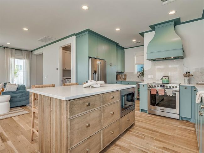 Kitchen with stainless steel appliances, premium range hood, tasteful backsplash, light wood-style flooring, and recessed lighting | Image 13