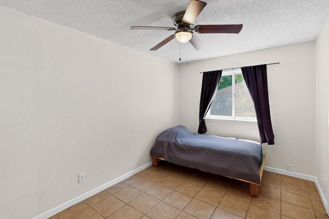 Bedroom featuring light tile patterned flooring, a textured ceiling, and a ceiling fan | Image 23