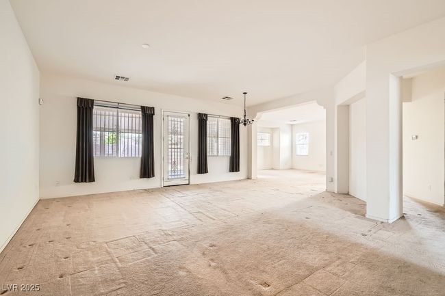 Spare room featuring carpet floors, plenty of natural light, a chandelier, and visible vents | Image 4