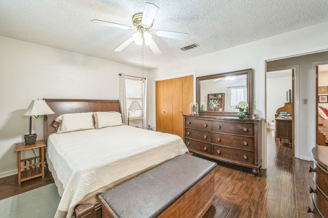 Bedroom featuring dark wood-type flooring, a textured ceiling, ceiling fan, and visible vents | Image 22