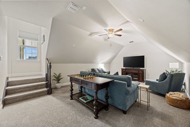 Carpeted living area featuring ceiling fan, lofted ceiling, baseboards, and stairs | Image 9