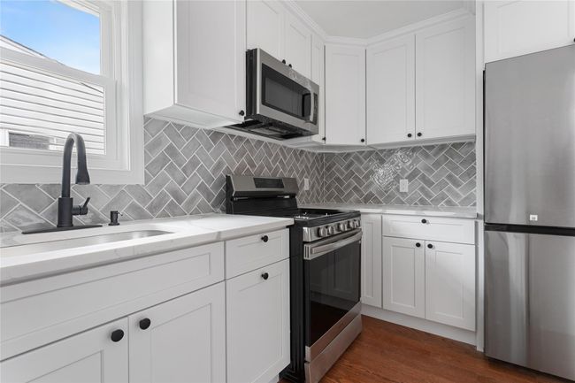 Kitchen featuring stainless steel appliances, a sink, white cabinets, and tasteful backsplash | Image 12