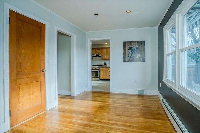 Unfurnished room featuring light wood-type flooring, ornamental molding, a wealth of natural light, and a baseboard heating unit | Image 12
