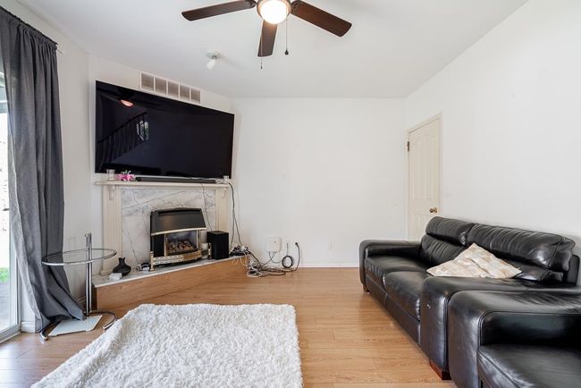 Living area with wood finished floors, a premium fireplace, a ceiling fan, and visible vents | Image 5
