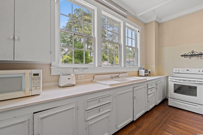 Kitchen with white appliances, crown molding, light countertops, and white cabinetry | Image 10