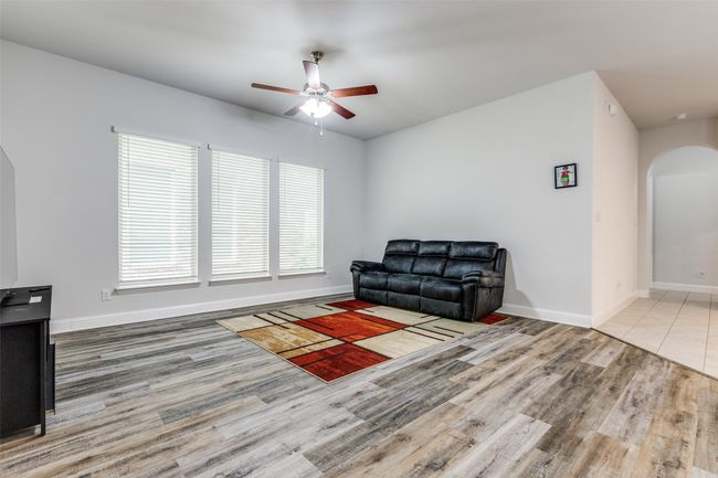 Living area featuring wood finished floors, a healthy amount of sunlight, arched walkways, and ceiling fan | Image 6