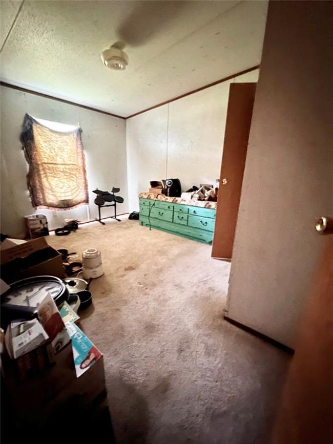 This room features carpeted flooring, a ceiling fan, and a single window. It appears to have ample space for storage or customization. The walls are plain, offering a neutral backdrop for personalization. | Image 8