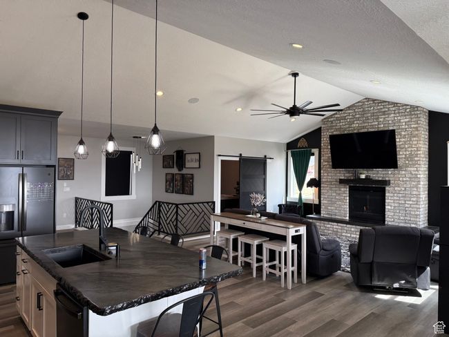 Kitchen with refrigerator with ice dispenser, a sink, a barn door, open floor plan, and ceiling fan | Image 7