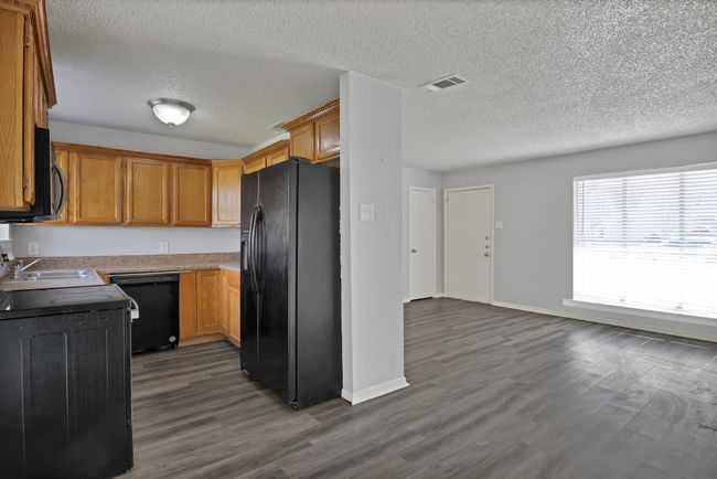 Kitchen featuring visible vents, black appliances, dark wood-style floors, light countertops, and baseboards | Image 7