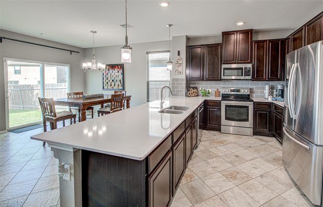 Kitchen featuring light countertops, tasteful backsplash, stainless steel appliances, and a sink | Image 11