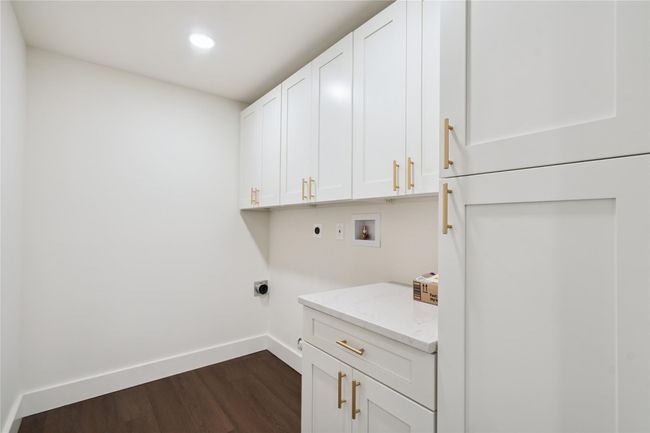 Laundry area featuring electric dryer hookup, cabinet space, washer hookup, dark wood-style floors, and recessed lighting | Image 32