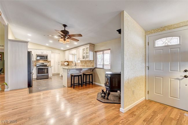 Kitchen with stainless steel appliances, a peninsula, a breakfast bar, a wood stove, and glass insert cabinets | Image 16